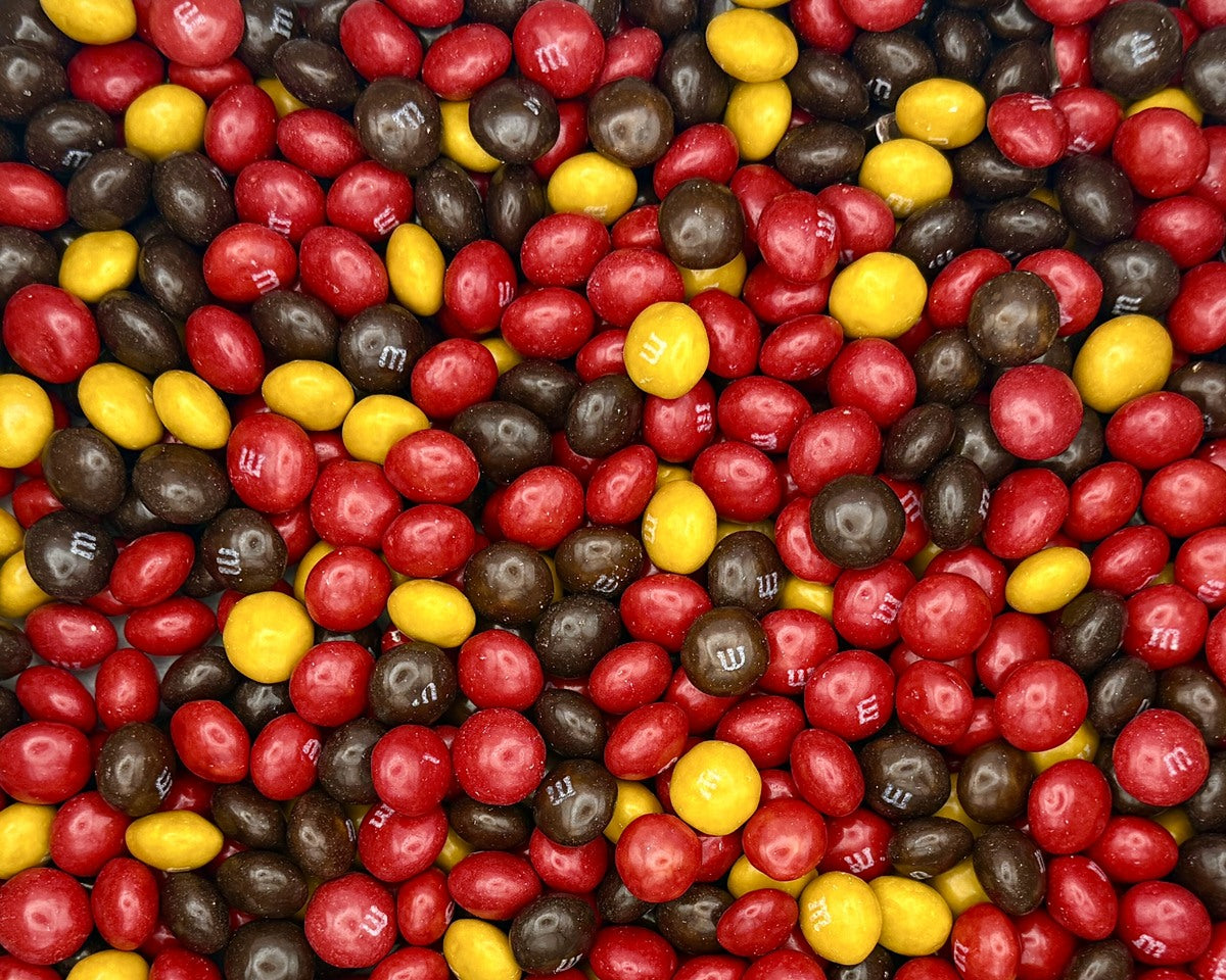 Assorted M&M candies in red, yellow, and brown on a white background